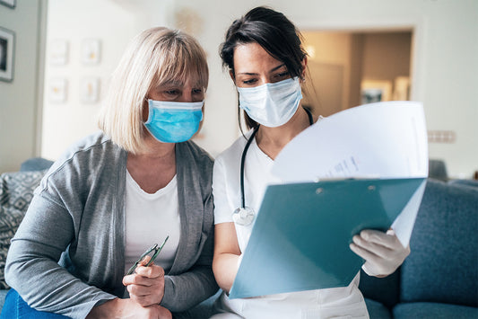 two women wearing face masks looking at a clipboard while discussing menopause treatment options