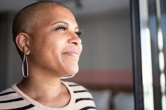 A woman looking out the window and smiling because Versalie is helping her figure out and learn more about menopause