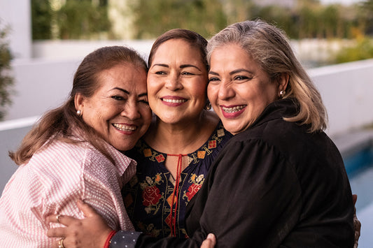 three woman smiling and hugging each other in support of each other's menopause stages