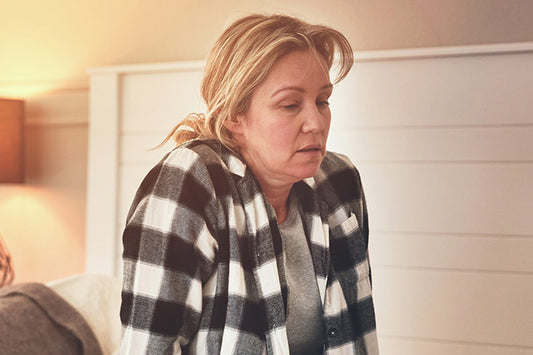 a woman experiencing menopause fatigue sitting on the edge of her bed