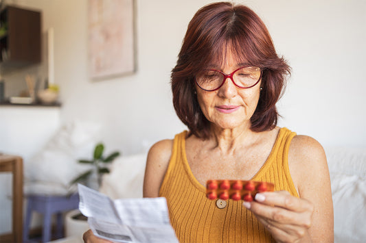 a woman reviewing medication instructions and a blister pack of her Menopausal Hormone Therapy (MHT)