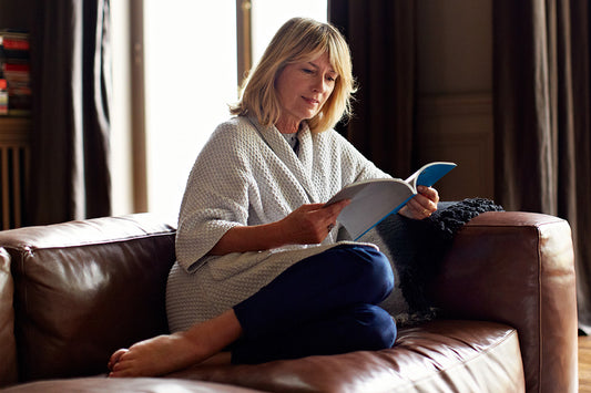 woman sitting on a couch reviewing her menopause checklist before she talks to her doctor about menopause