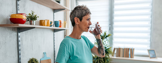 Woman in perimenopause sipping water throughout the day to help stay hydrated during menopause