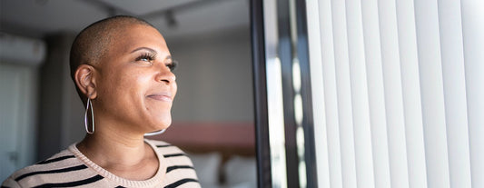 A woman looking out the window and smiling because Versalie is helping her figure out and learn more about menopause