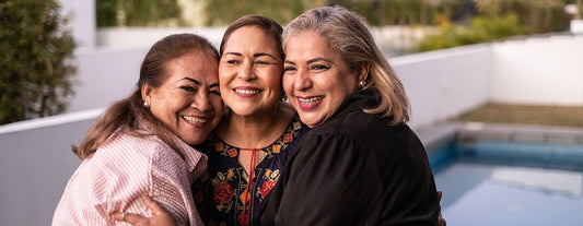 three woman smiling and hugging each other in support of each other's menopause stages