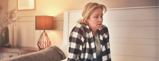 a woman experiencing menopause fatigue sitting on the edge of her bed