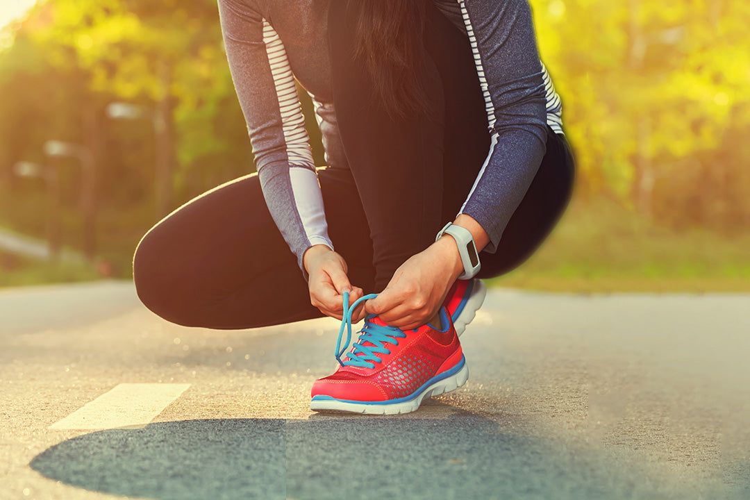 a woman tying her shoelaces when working out in the heat during menopause