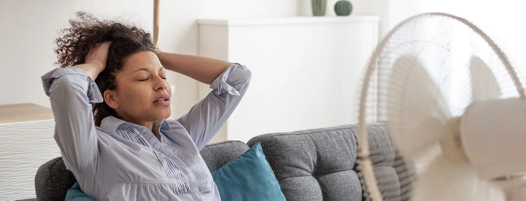 woman in menopause sitting in front a fan looking for options for supplement for hot flashes