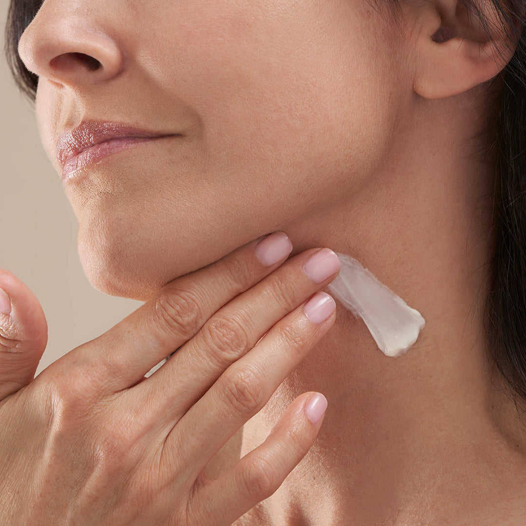 A woman in menopause applying the retinol face & neck cream to her aging skin