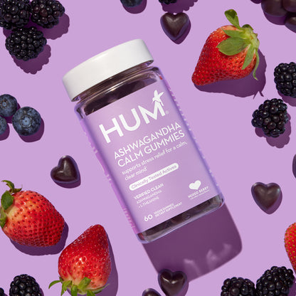 HUM NUTRITION Ashwagandha Calm gummies scattered next to bottle and mixed berries