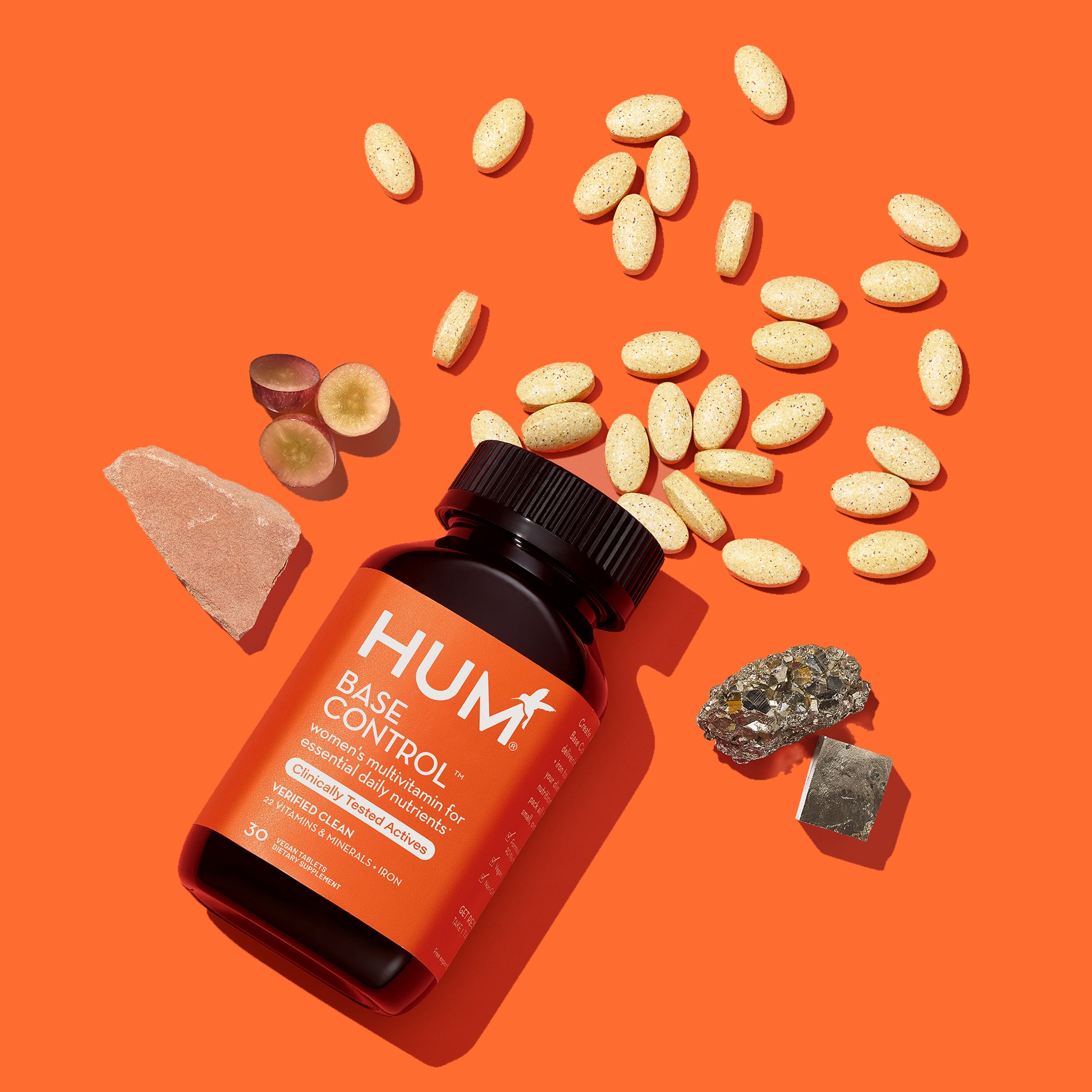 HUM NUTRITION Base Control vegan tablets scattered next to bottle and several ingredients