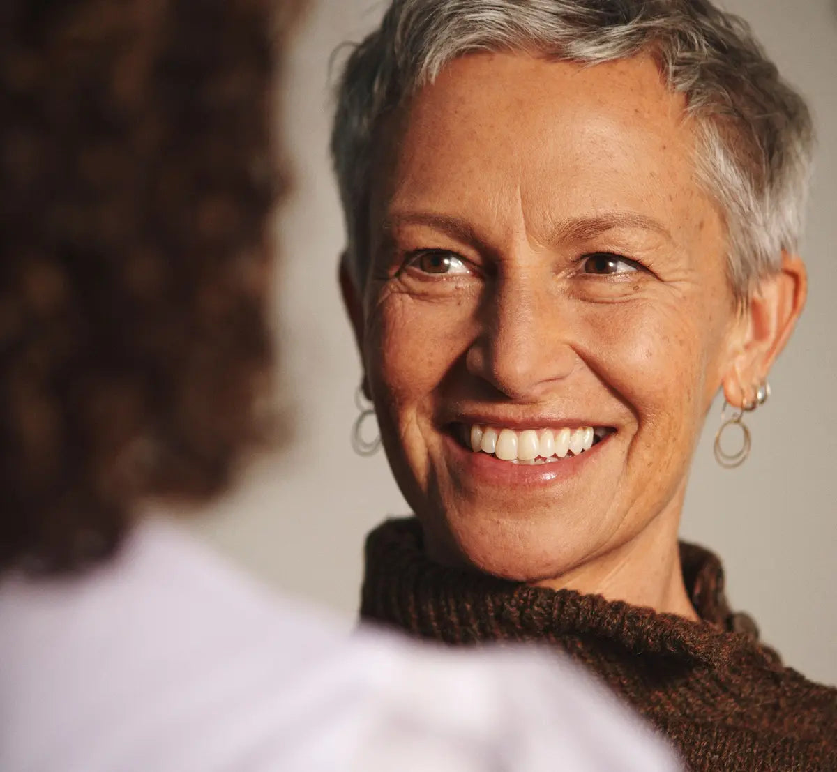 woman smiling and talking about menopause and how menopause experts can help 