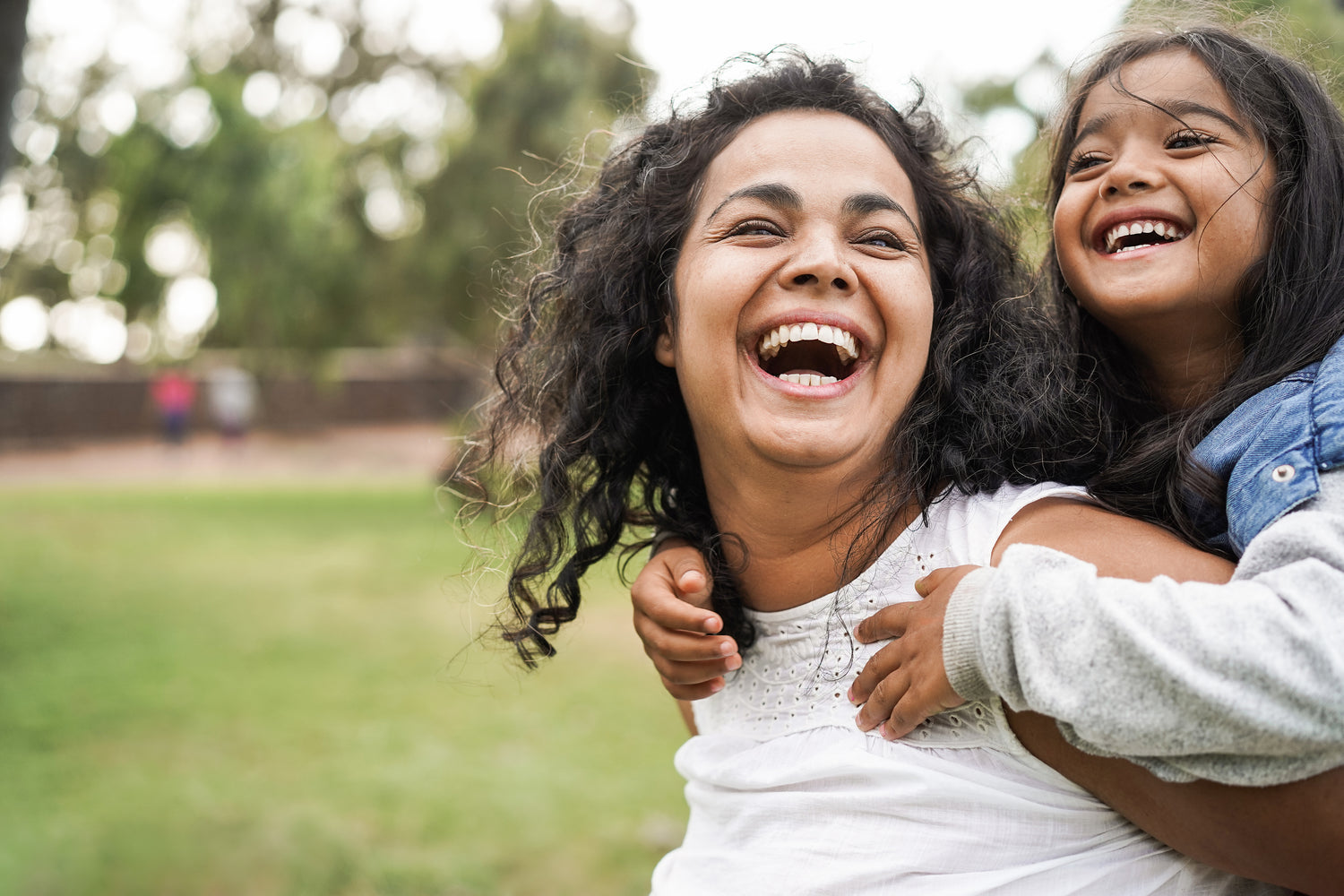 Menopausal woman with good oral hygiene & dental health smiling while carrying a young child